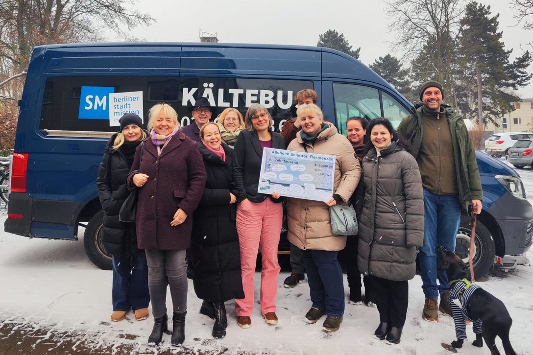 Karen Holzinger, Fachbereichsleitung Wohnungslosenhilfe der Berliner Stadtmission (sechste von links, Bildmitte), nahm den symbolischen Scheck über 10.000 Euro von den Einrichtungsleitern und Mitarbeitern der Berliner Alloheim Senioren-Residenzen entgegen.