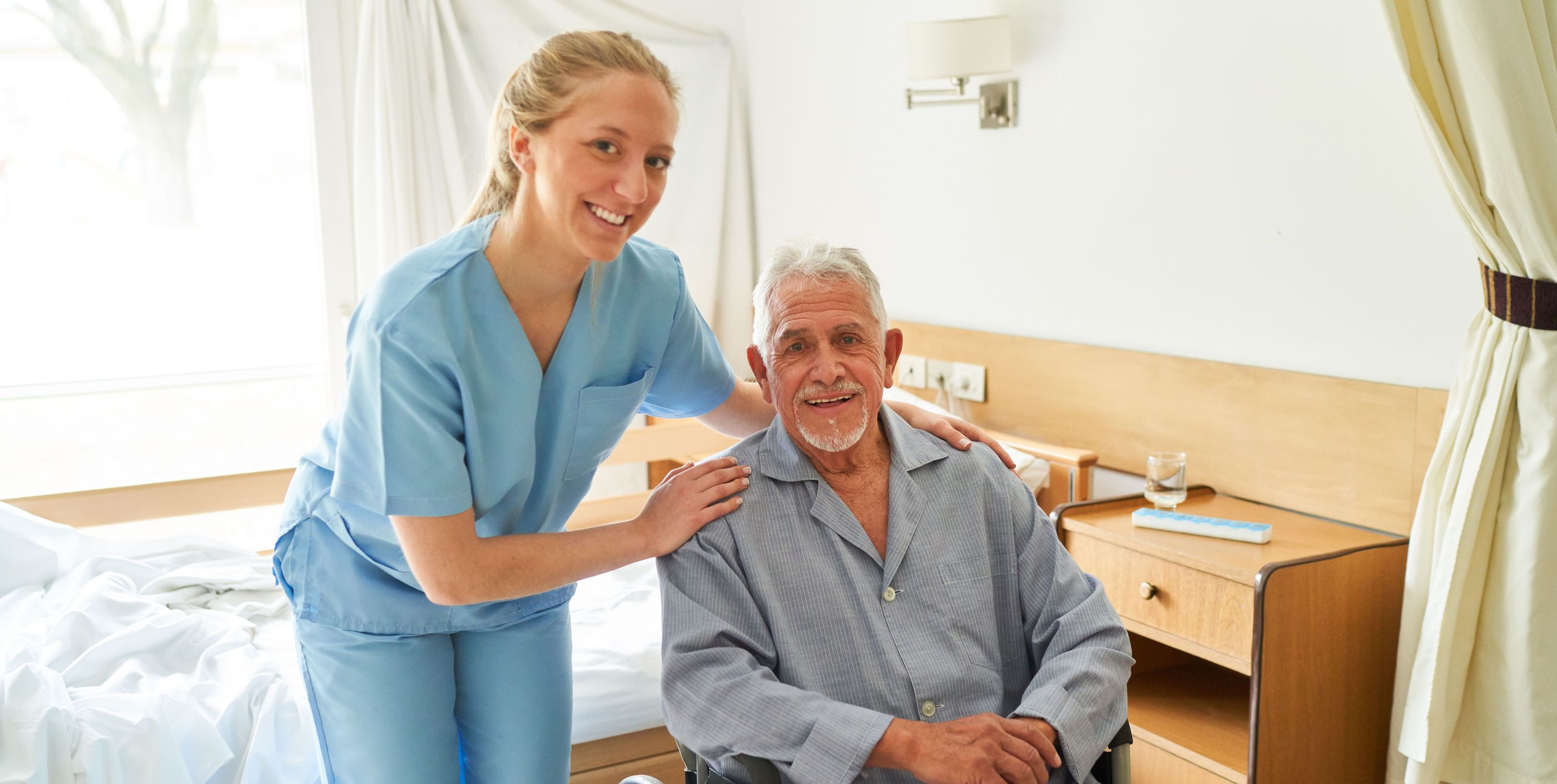 Smiling nurse with elderly man in wheelchair at rehab center
