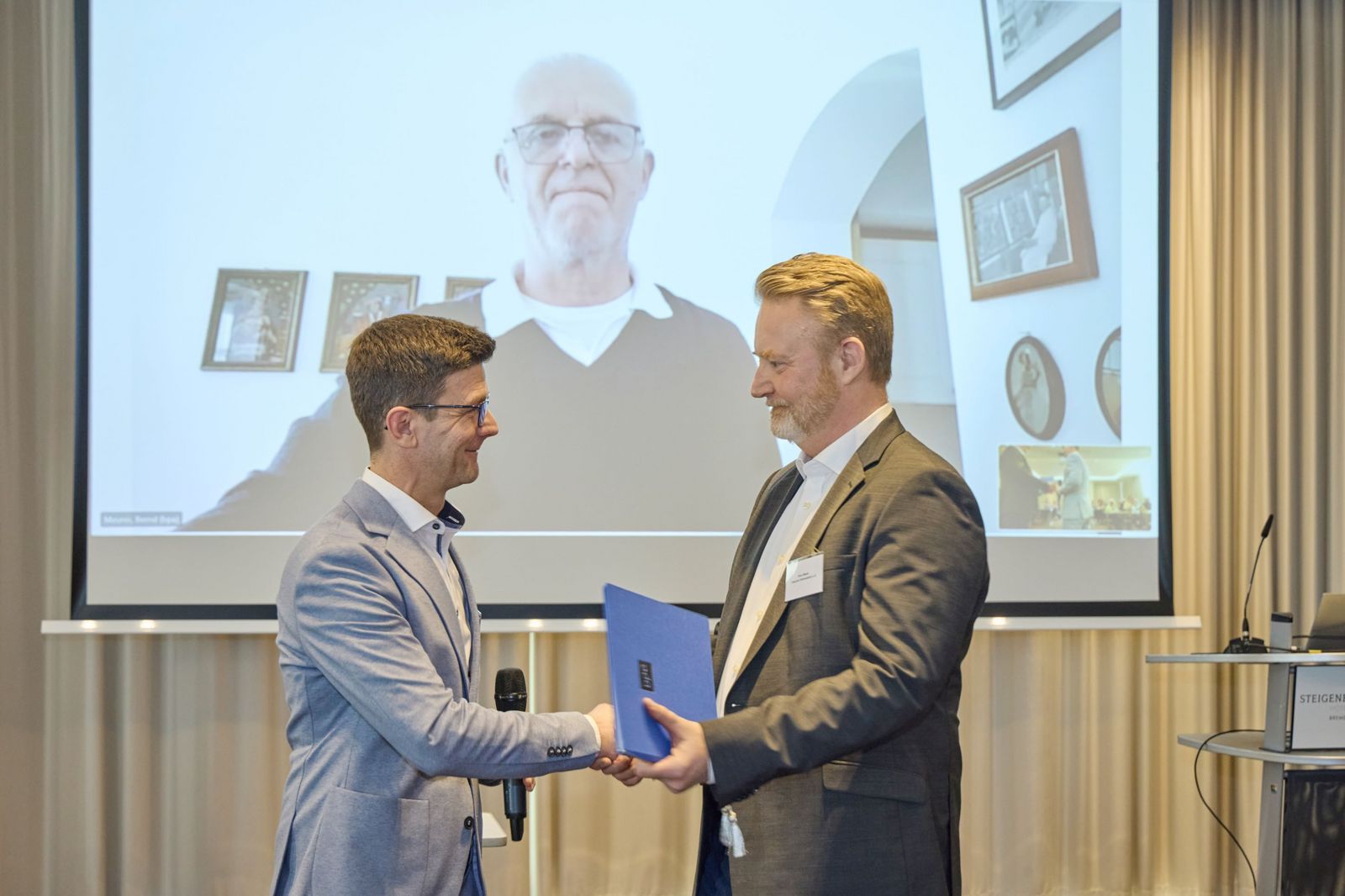 bpa-Hauptgeschäftsführer Norbert Grote gratuliert dem ehemaligen bpa-Landesvorsitzenden Sven Beyer und überreicht ihm im Namen von bpa-Präsidend Bernd  Meurer (im Hintergrund zugeschaltet) die goldene Ehrennadel samt Urkunde